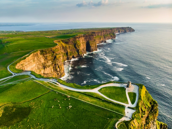 Klippen an der Küste mit grünen Wiesen und Meer im Hintergrund.