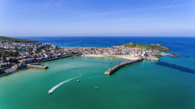 Küstenstadt mit Hafen, Booten und blauem Meer aus der Luftansicht.