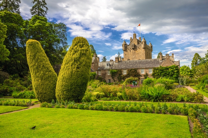 Cawdor Castle in Schottland mit gepflegtem Garten und Zierbrunnen an einem Sommertag.
