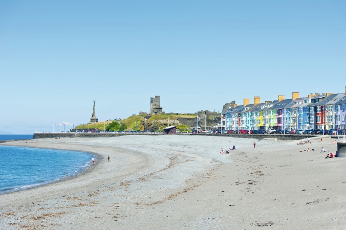 Strand mit farbigen Häusern und einer Burg im Hintergrund an der Küste.
