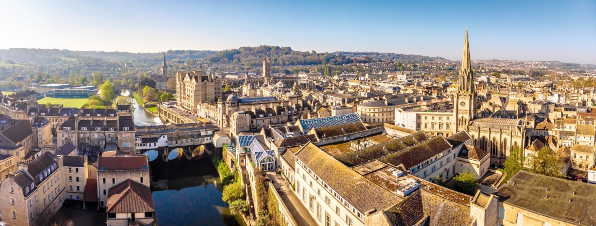 Panorama einer historischen Stadt mit Fluss und Kirche im Sonnenschein.