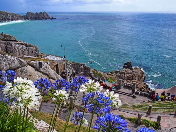 Felsenbucht mit Theater, blühenden Blumen und Blick aufs Meer.